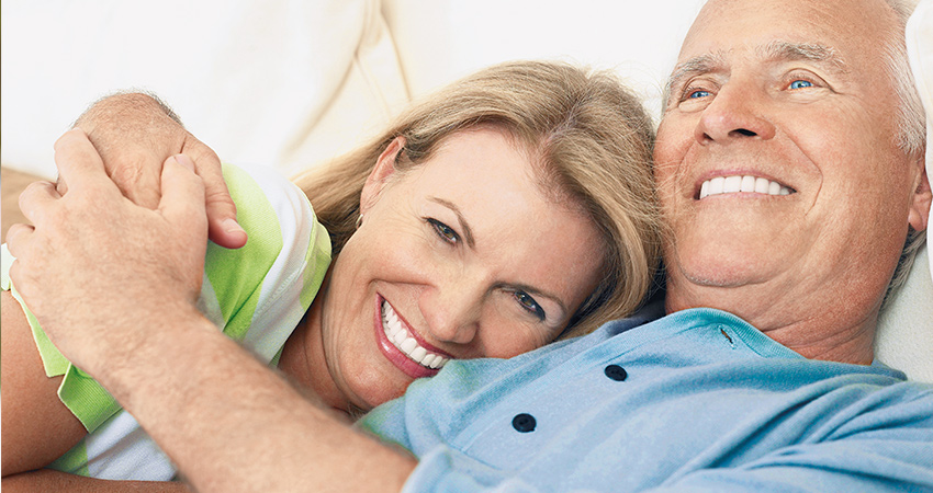 Older couple smiles and cuddles in bed